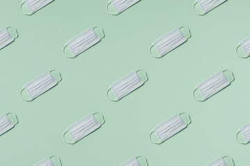 medicine, healthcare and pharmacy concept - medical masks lie in rows diagonal on mint green background top view copy space pattern.