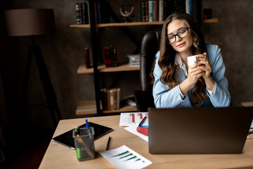 Business conception.Beautiful business lady in blue suit with cup of coffee in the office.