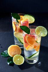 Health care, fitness, healthy nutrition diet concept. Fresh cool homemade citrus infused detox water with grapefruit, orange, lemon and lime and ice in glasses on dark background.