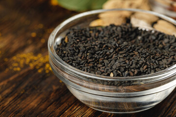 Glass bowl of black sesame on dark wooden table
