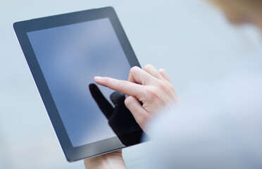 Close-up of woman's finger pressing on a digital tablet touchscreen device. Online shopping/banking concept.