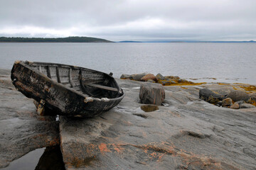 Karelian landscape. Traditional pomor wooden boat on the rocky shore of Kandalaksha Gulf of White Sea. Republic of Karelia, Russia.