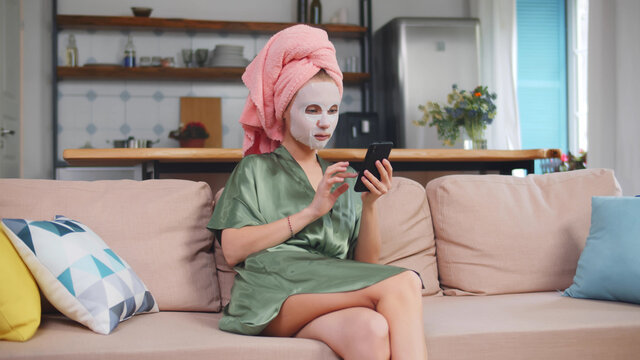 Portrait of a woman with face mask using phone on sofa