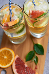 Health care, fitness, healthy nutrition diet concept. Fresh cool homemade citrus infused detox water with grapefruit, orange, lemon and lime and ice in a jug and glasses for spring summer days.