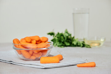 nature, diet and healthy food concept - view of fresh baby peeled carrots and glass of water and oil and herbs on the background. Copy space