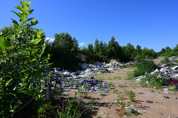 Horizontal photo of garbage in a field against a blue sky in summer sunny weather
