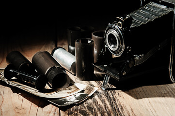 Vintage camera, photographic film and old photos on a wooden table