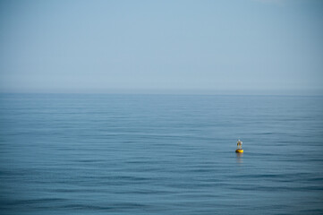 floating yellow signal buoy on blue sea with copy space