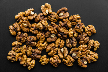 Walnut scattered on a black table. Walnuts is a healthy vegetarian protein nutritious food. Natural nuts snacks.