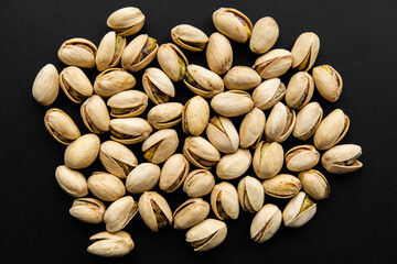 Pistachios scattered on a black table. Pistachio is a healthy vegetarian protein nutritious food. Natural nuts snacks.