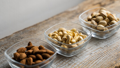 Almond, pistachio and cashew in a small plates which standing on a vintage white table. Nuts is a healthy vegetarian protein and nutritious food.
