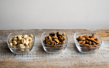 Almond, pistachio and walnut in a small plates which standing on a vintage white table. Nuts is a healthy vegetarian protein and nutritious food.