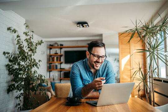 Portrait Of A Handsome Man Laughing While Looking At Laptop.