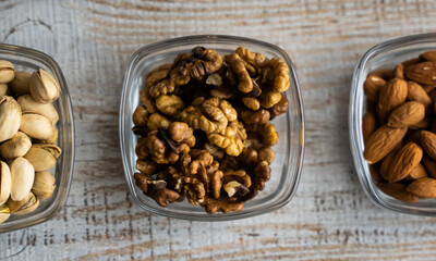 Almond, pistachio and walnut in a small plates which standing on a vintage white table. Nuts is a healthy vegetarian protein and nutritious food.