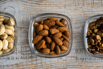 Almond, pistachio and walnut in a small plates which standing on a vintage white table. Nuts is a healthy vegetarian protein and nutritious food.