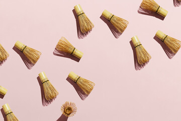 Flatlay of bamboo matcha tea whisks on pink pastel background