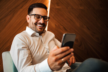 Close-up portrait of a successful smiling entrepreneur using smart phone, indoors, copy space.
