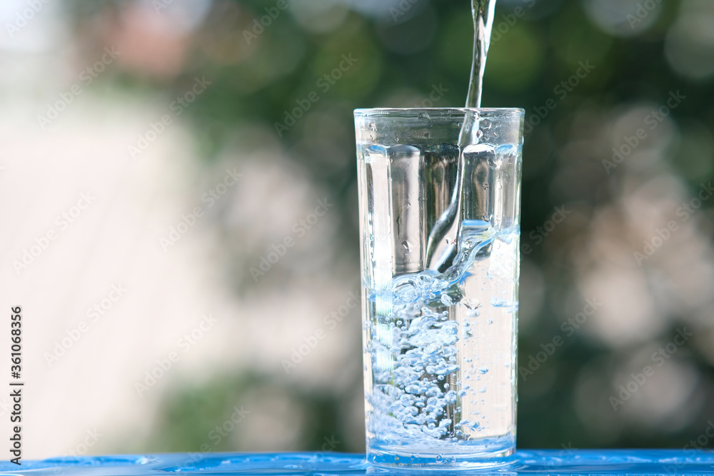 Poster glass of water on wood table background and pouring drinking water