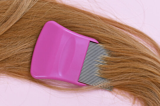 Strand of blond hair with lice comb on light pink background