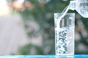 glass of water on wood table background and pouring drinking water