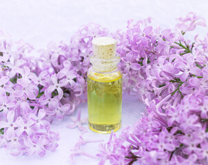 Fototapeta na wymiar Glass bottle with aromatic yellow oil and lilac flowers for Spa and aromatherapy. Electoral focus