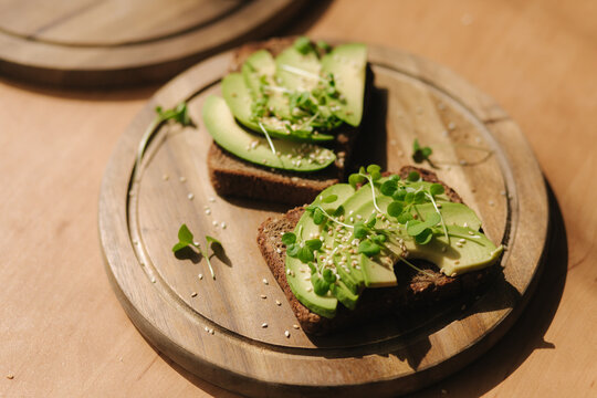 Avocado toast on wooden boadr. Vegetarian food concept. Fresh food at home. Sandwich with avocado and rye toasted bread, sesame seeds and mustard seedings
