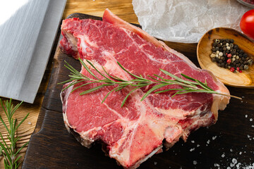 Raw T-bone steak with herbs on wooden board