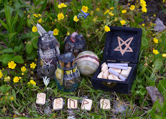 Witch decorated bottles with potion, runes and crystal ball in the garden. Esoteric, gothic and occult background with magic objects, mystic and fairy tale concept outdoors.