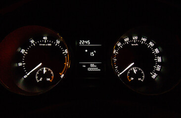 Fototapeta Autoblogs and maintenance. Dashboard of a passenger car with a mileage figure of 100,000 kilometers on an odometer on a black background. Use for topics of car service, transport, cars and operation. obraz