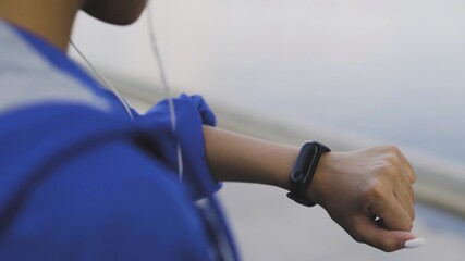 Afro-american runner woman looking at fitness bracelet before jogging