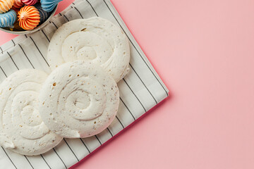 White meringue cookie on pink background with colorful mini meringues - obrazy, fototapety, plakaty