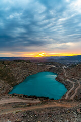 Fototapeta premium Sunrise over the blue quarry lake in the shape of a heart. Limestone fluxing of Kadykovo quarry, Balaklava, Crimea. A place for a photo shoot, tourism, beautiful places.