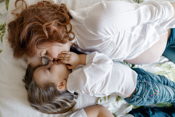 Mother daughter moments. pregnant woman lying on the bed with her little girl