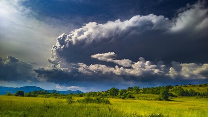 Horizontal shot dramatic puffy clouds over a green field