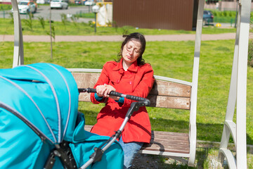 Tired mother with baby stroller outdoors.