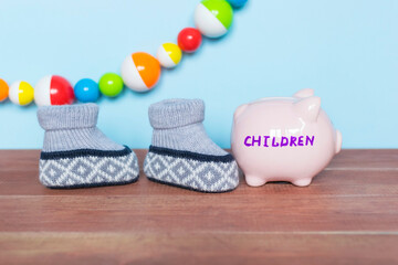 Piggy bank with word Children, toys and clothes on the wooden table,expenses on babies concept.