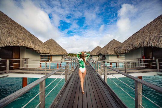 beautiful girl in swimsuit posing on dock, tropical resort in background
