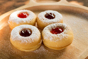 tasty donuts with blueberry and strawberry jam sprinkle with icing sugar put on wooden dish. Hanukkah celebration (Festival of lights). Top view photography.