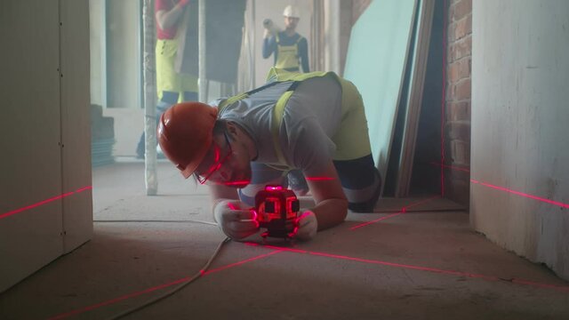 Builder adjusting laser level on floor before measure