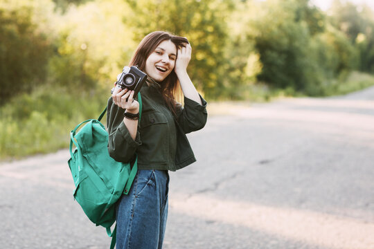 A smiling girl holds a camera in her hands. The girl travels and takes photos of landscapes on a vintage camera. Space for text