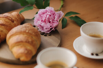 Vegan breakfast at home. Cappuccino with coconut milk and two empty vegan croissants. Morning with coffe. Pink peony flower on table