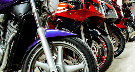 Beautiful group parking of motorcycles in a showroom for sale, in a store close-up. Maintenance of sportbikes, road bikes in the workshop. Moto parts, wheels, headlights, engine. Banner for web site