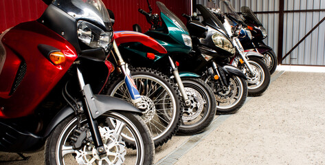Colored sports, road beautiful bikes in a motor show. Many motorcycles parked in a store. Sale of used cruise motorbikes in the cabin. Showroom equipment in the garage. Banner for web site