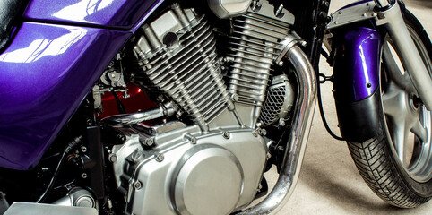 Silver v-twin shaped engine of sports motorcycle close-up. Pistons, cylinders, pedals, gearbox, front wheel motorbike. Chrome motor parts. Repair, bike maintenance in the garage. Banner for web site