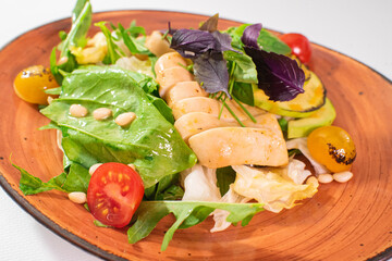 Tasty salad with grilled squid and avocado on a white background