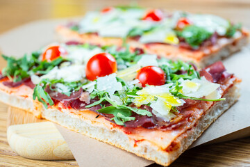 pizza with cherry tomatoes, parmesan cheese, arugula and smoked ham