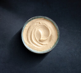 Humus en bol sobre fondo negro. Hummus in a bowl on a black background.