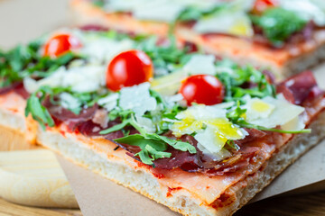 pizza with cherry tomatoes, parmesan cheese, arugula and smoked ham