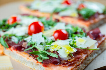pizza with cherry tomatoes, parmesan cheese, arugula and smoked ham