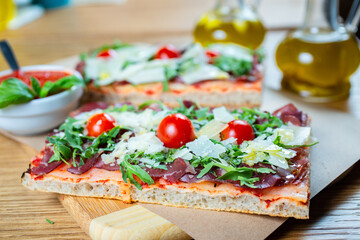 pizza with cherry tomatoes, parmesan cheese, arugula and smoked ham